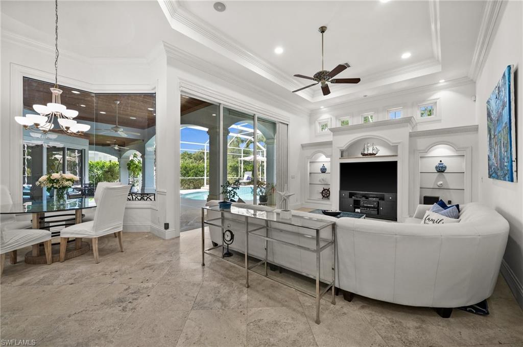 6898 Mill Run Road Naples, FL 34109 - Photo 12 of 38 a living room with furniture a chandelier and a flat screen tv