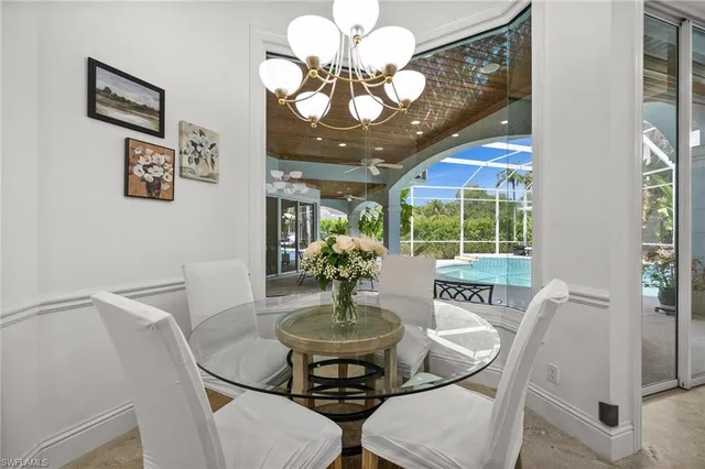 a view of a dining room with furniture a chandelier and large windows