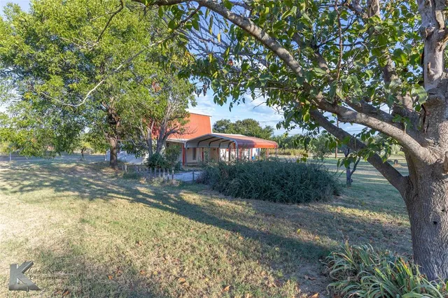 a view of a house with backyard and trees