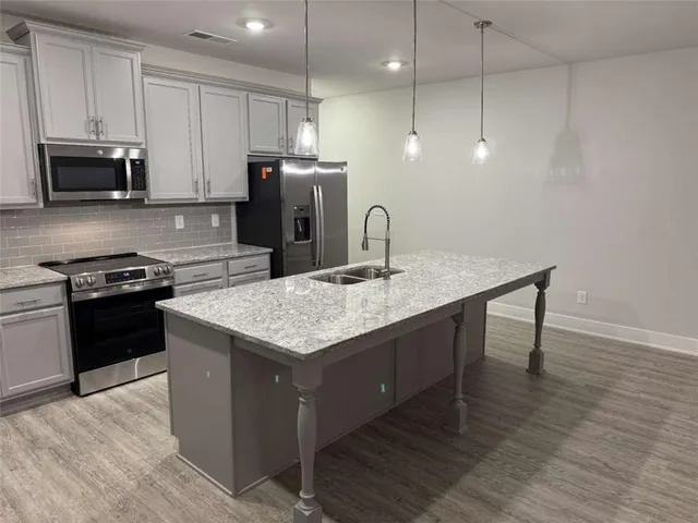 a kitchen with kitchen island a counter space a sink appliances and cabinets