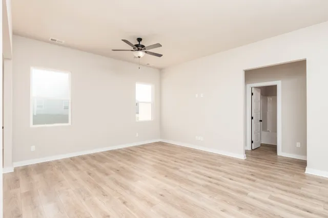 a view of empty room with wooden floor and fan