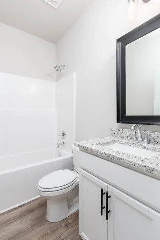 a bathroom with a granite countertop toilet sink a mirror and shower