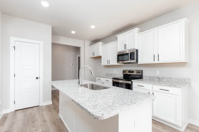 a kitchen with stainless steel appliances granite countertop a sink stove microwave and refrigerator