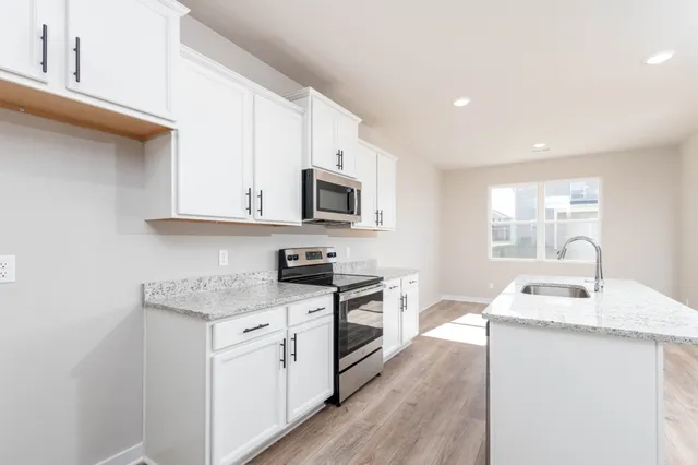 a kitchen with granite countertop white cabinets sink and stainless steel appliances