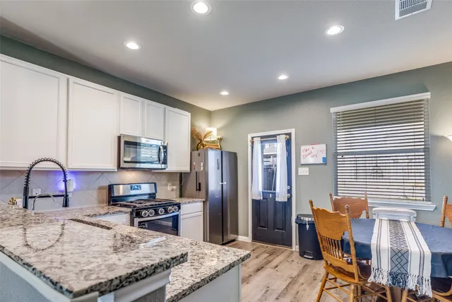 a kitchen with stainless steel appliances granite countertop a sink refrigerator and cabinets