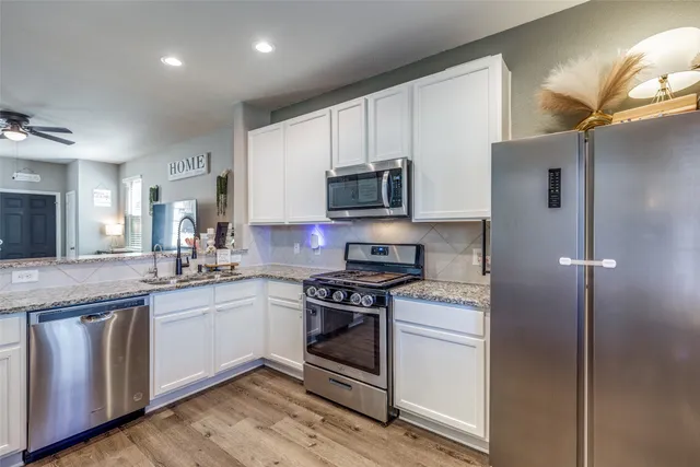 a kitchen with stainless steel appliances granite countertop a stove a sink and a refrigerator