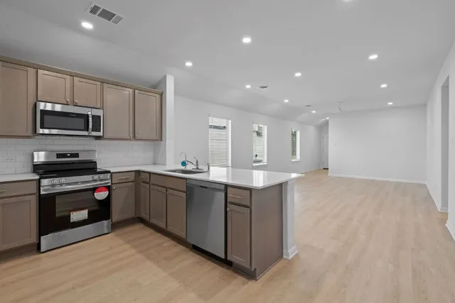 a large kitchen with stainless steel appliances granite countertop a stove a sink and a microwave