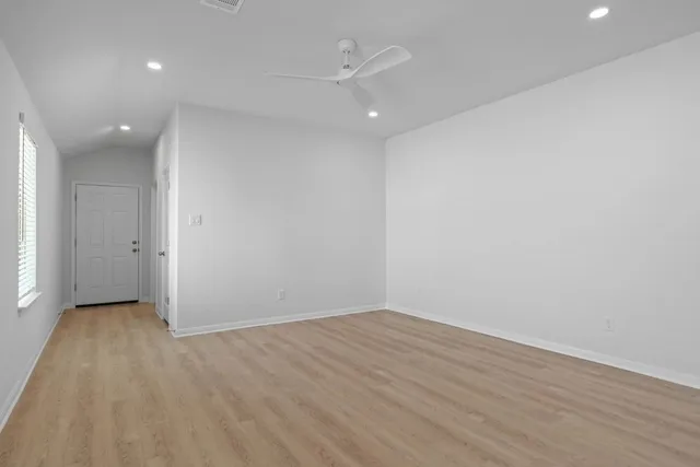 an empty room with wooden floor and a ceiling fan