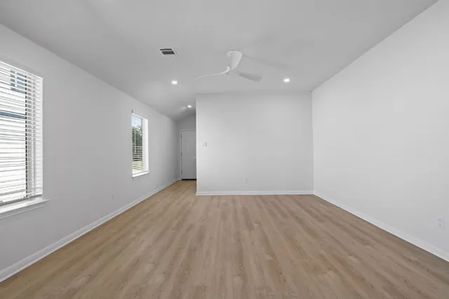 an empty room with wooden floor and windows