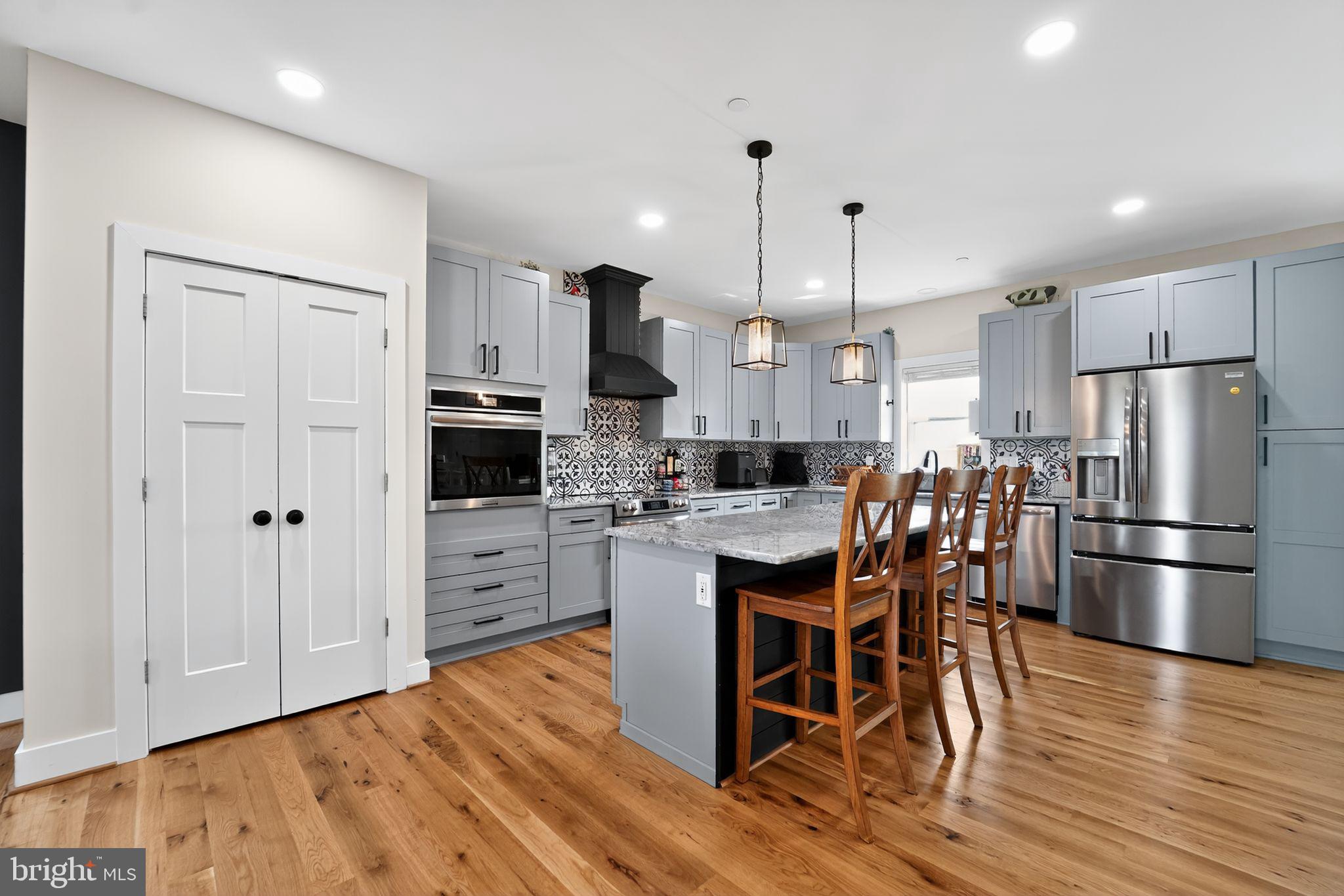 8305 Biggs Ford Road Walkersville, MD 21793 - Photo 6 of 38 a kitchen with stainless steel appliances a refrigerator a stove a sink a dining table and chairs with wooden floor