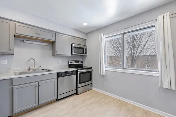 a kitchen with stainless steel appliances granite countertop a sink a stove a refrigerator with grey cabinets