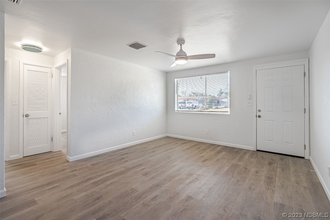 909 Derbyshire Road Daytona Beach, FL 32117 - Photo 11 of 18 an empty room with wooden floor chandelier and windows