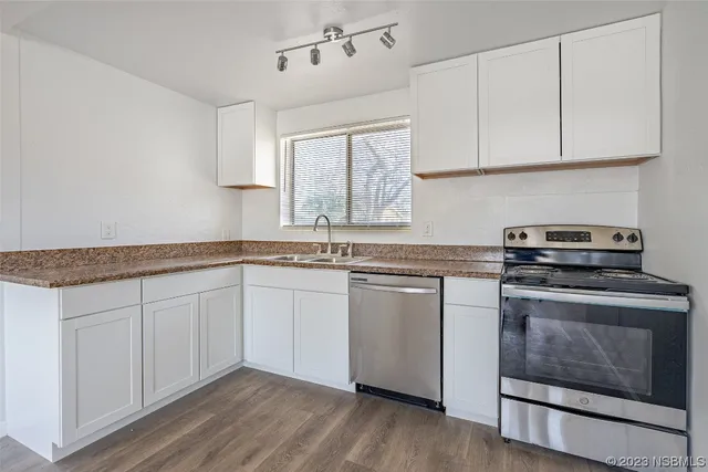 a kitchen with granite countertop a sink cabinets and stainless steel appliances