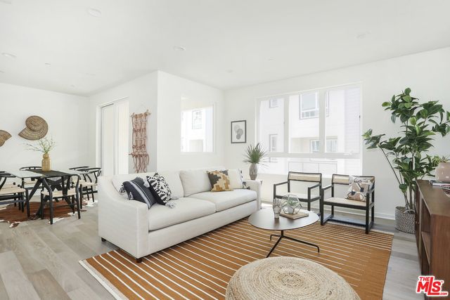 a living room with furniture a dining table with wooden floor and potted plants