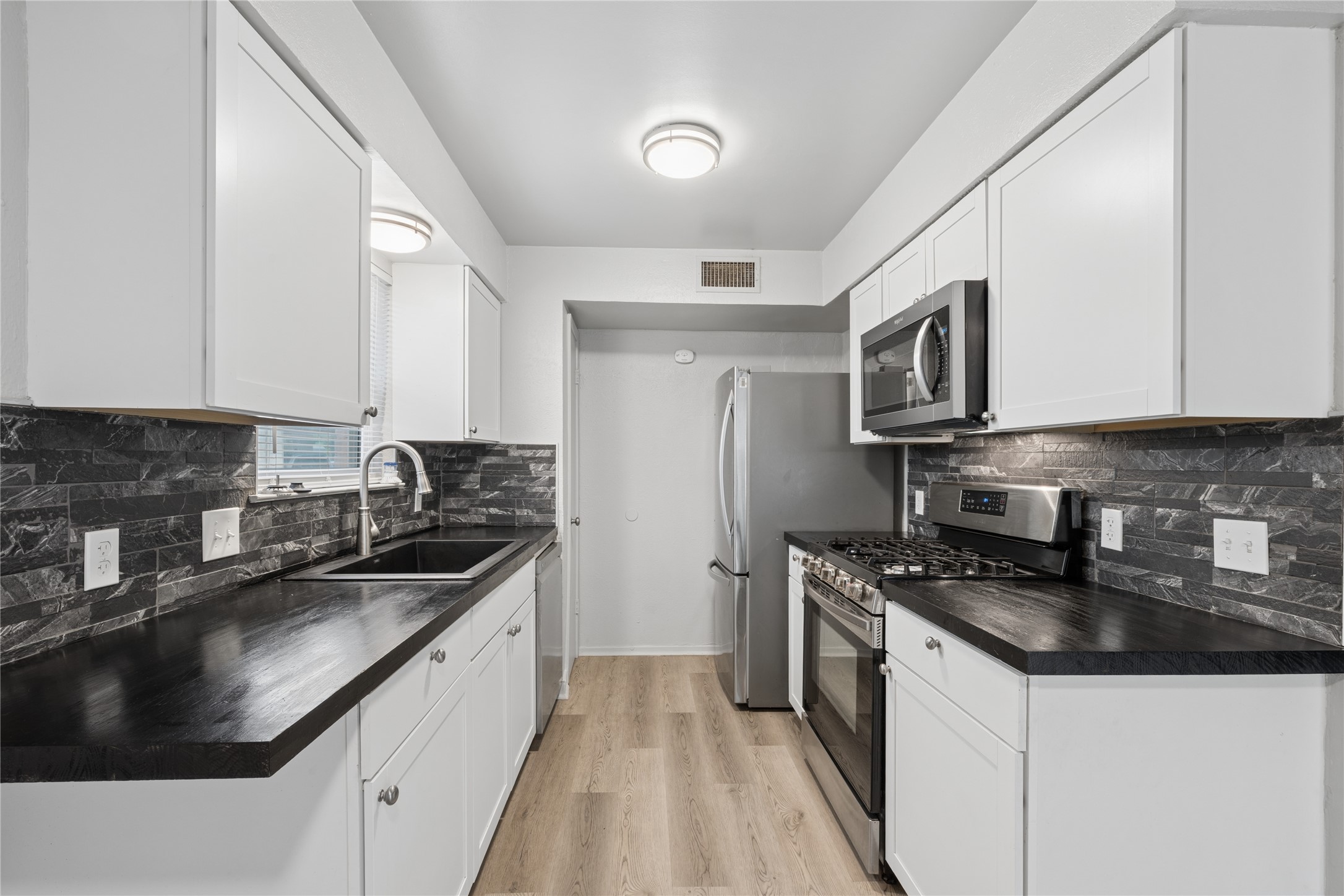 820 Sahara Avenue, Unit B Austin, TX 78745 - Photo 15 of 29 a kitchen with stainless steel appliances granite countertop a sink stove microwave and refrigerator