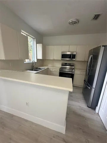 a kitchen with a sink a window and cabinets