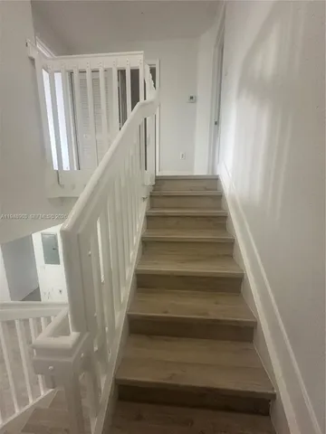 a view of a hallway with wooden floor and staircase