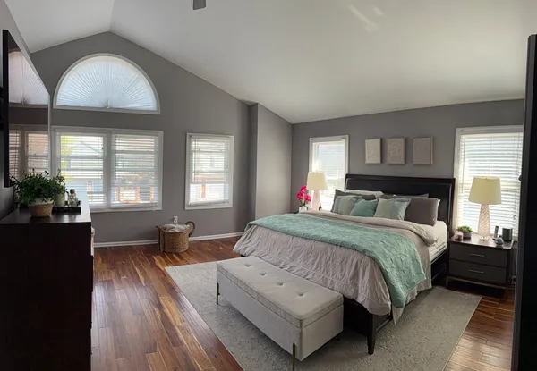 a spacious bedroom with a bed and wooden floor