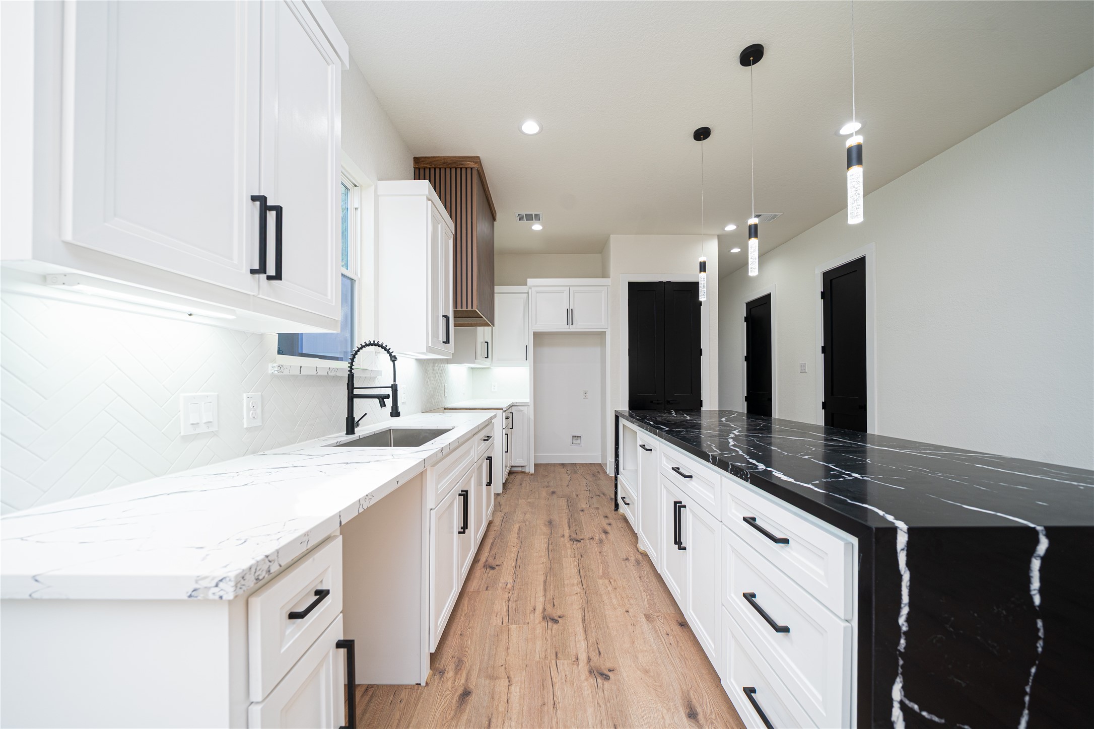 a large white kitchen with a large counter top a sink a stove and a refrigerator