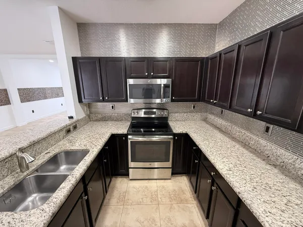 a large kitchen with granite countertop a stove and a sink