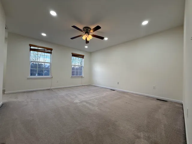 an empty room with windows and chandelier fan