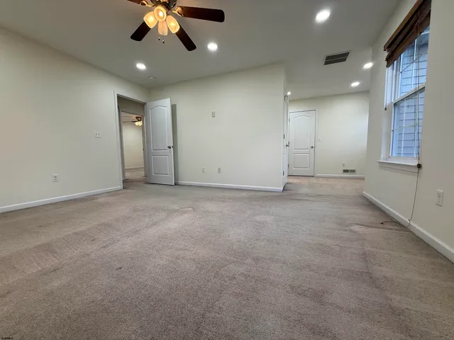 an empty room with a ceiling fan and window