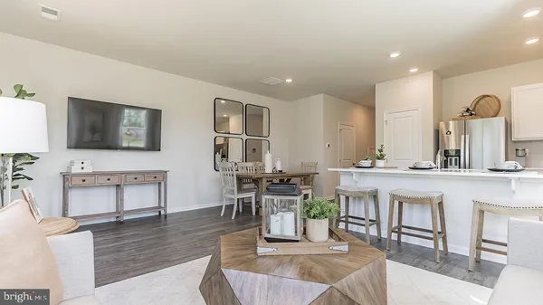 a living room with furniture a flat screen tv and kitchen view