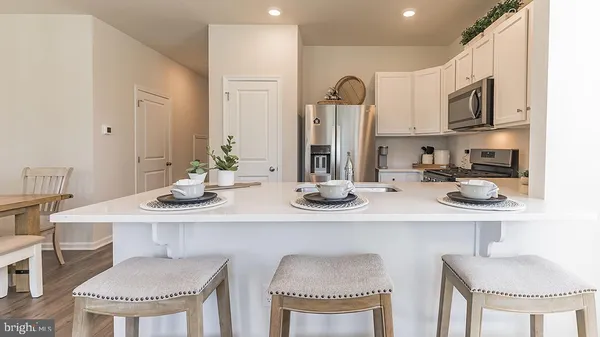 a kitchen with stainless steel appliances kitchen island granite countertop a dining table chairs and a refrigerator