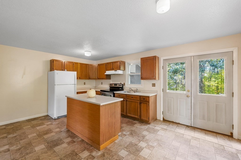 756 Bemis Road Warren, MA 01585 - Photo 30 of 41 a kitchen with a refrigerator a stove a microwave a sink and a dining table with wooden floor