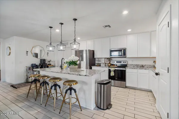a large kitchen with granite countertop stools a sink a counter space and stainless steel appliances
