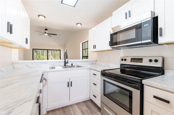a kitchen with cabinets stainless steel appliances and wooden floor