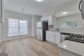 a kitchen with a refrigerator a sink and white cabinets