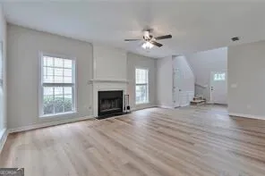 an empty room with windows fireplace and wooden floor