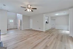 an empty room with wooden floor and a ceiling fan
