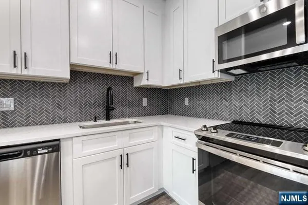 a kitchen with granite countertop white cabinets and stainless steel appliances