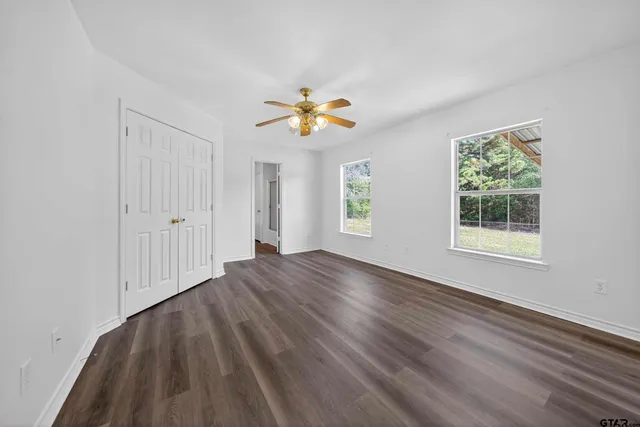 a view of an empty room with window and wooden floor