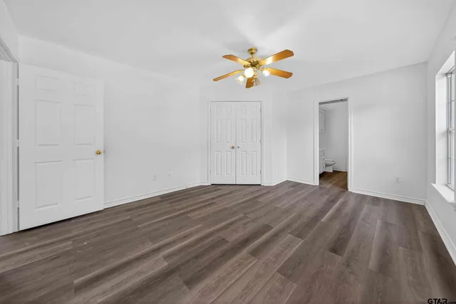 a view of an empty room with wooden floor and window