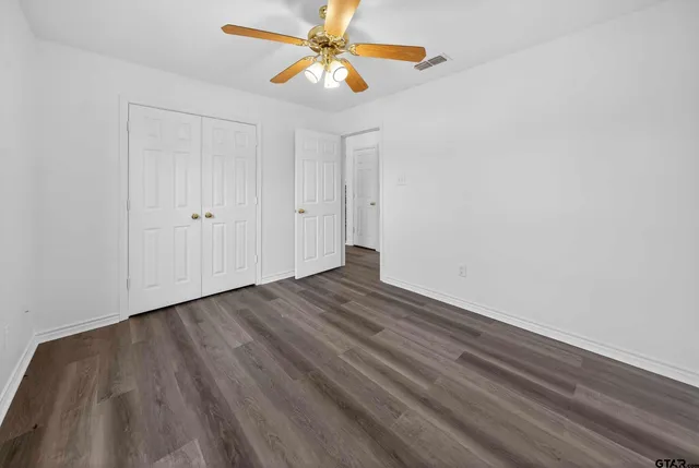 a view of a room with wooden floor and a ceiling fan