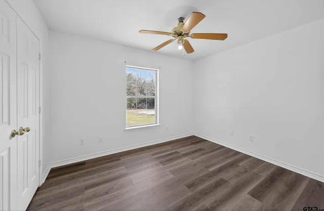 a view of a big room with wooden floor and windows