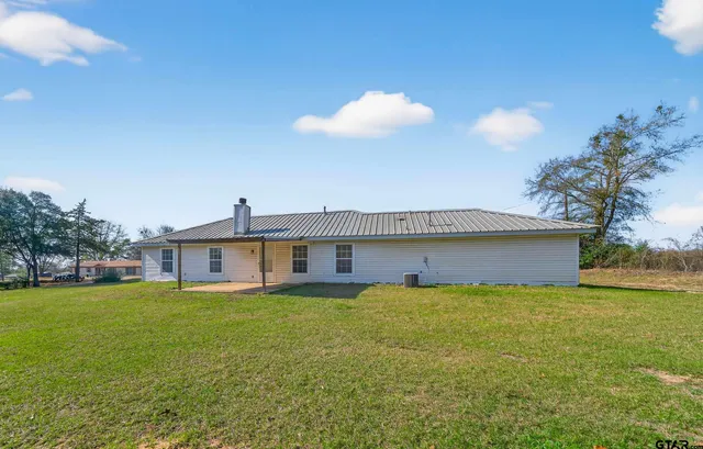 a view of a house with a yard and a large tree