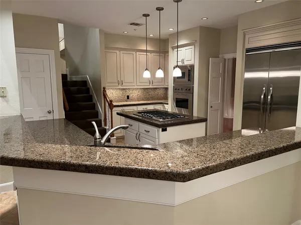 a kitchen with kitchen island granite countertop a stove and a refrigerator