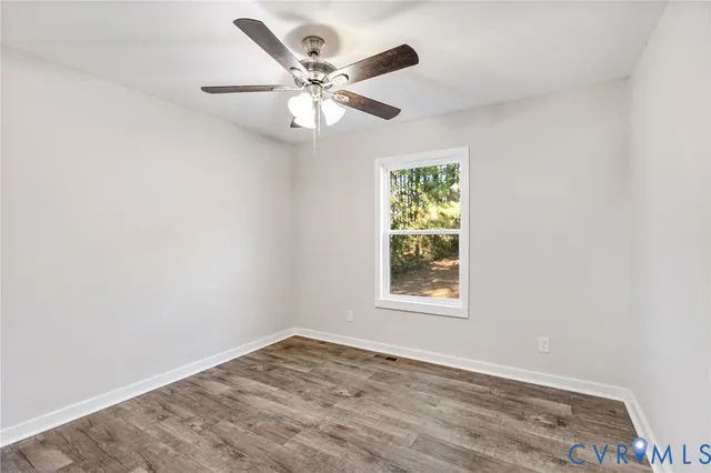 an empty room with wooden floor fan and windows