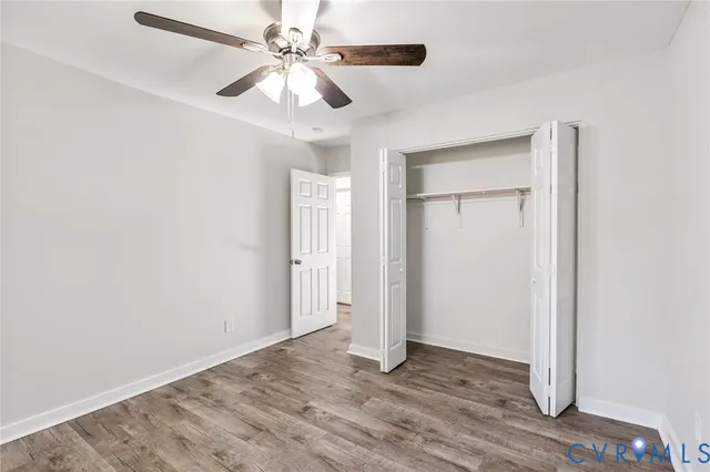 an empty room with wooden floor ceiling fan and windows