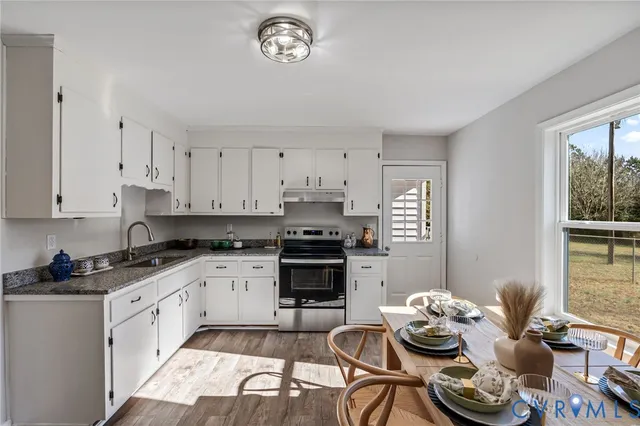 a kitchen with stainless steel appliances kitchen island granite countertop a stove a sink and a white cabinets