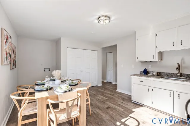 a kitchen with stainless steel appliances kitchen island granite countertop a sink a stove a dining table and chairs with white cabinets