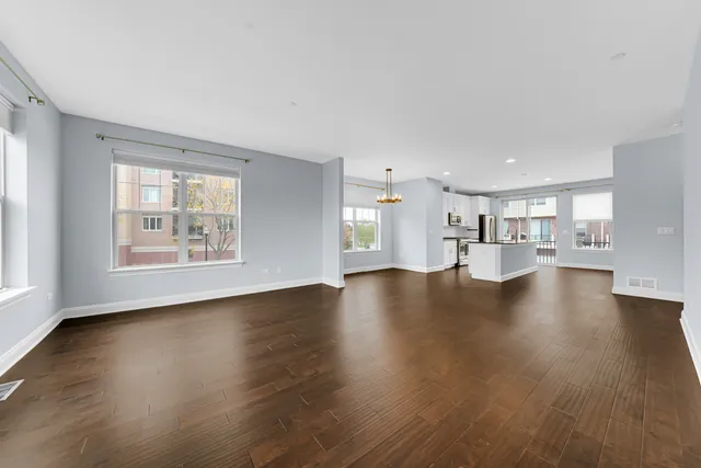 a view of empty room with wooden floor and a window