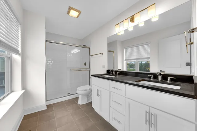 a bathroom with a sink a toilet a mirror and a shower