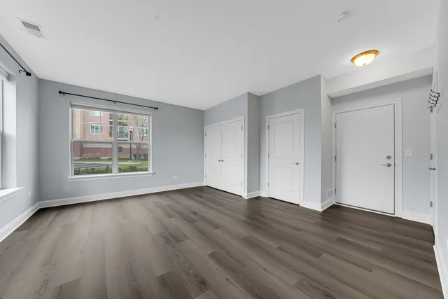 an empty room with wooden floor and windows
