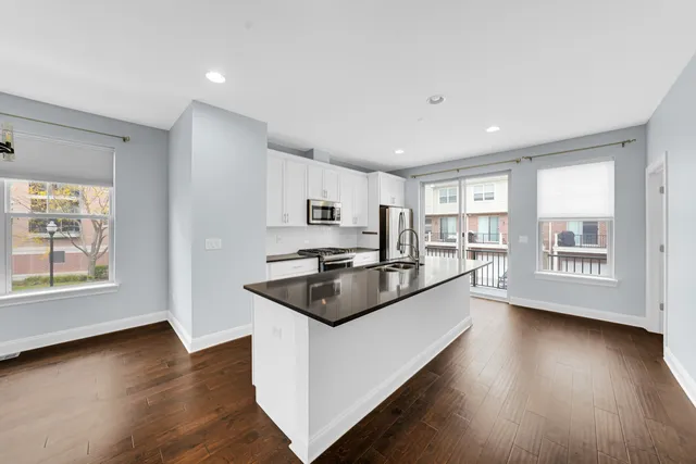 a kitchen with stainless steel appliances granite countertop a sink a stove a refrigerator and wooden floor