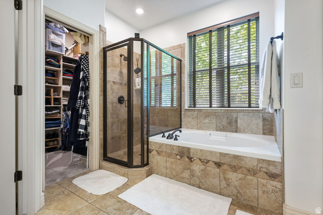 882 Sego Lily Way Mapleton, UT 84664 - Photo 18 of 41 Tiled bath area featuring a corner shower with a dark framed glass enclosure, a built-in soaking tub with a tiled surround, and an adjacent organized closet with built-in shelving